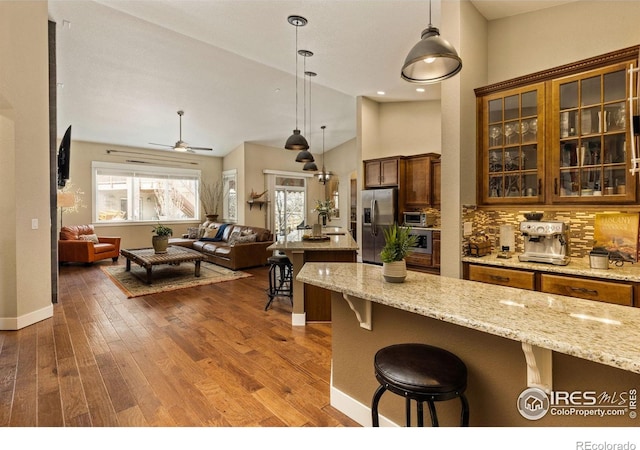 1963 Blue Yonder Way, Fort Collins, CO 80525 - kitchen featuring stainless steel fridge with ice dispenser, a breakfast bar, open floor plan, pendant lighting, and dark wood-style floors