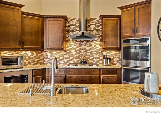 1963 Blue Yonder Way, Fort Collins, CO 80525 - kitchen with appliances with stainless steel finishes, wall chimney range hood, backsplash, and light stone countertops