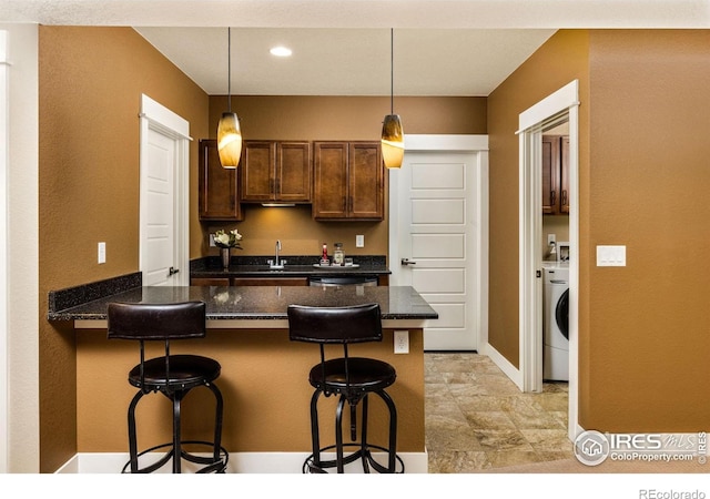 1963 Blue Yonder Way, Fort Collins, CO 80525 - kitchen featuring a peninsula, a breakfast bar area, decorative light fixtures, washer / clothes dryer, and recessed lighting