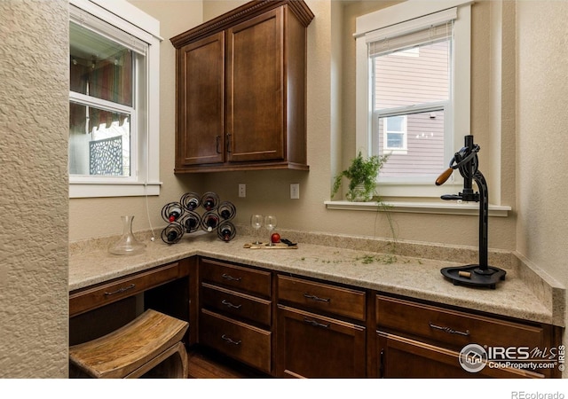 1963 Blue Yonder Way, Fort Collins, CO 80525 - kitchen with dark brown cabinetry, a textured wall, and light stone countertops