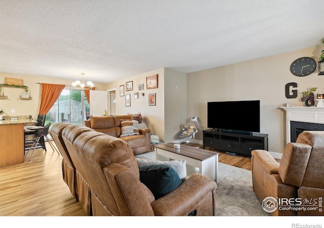 1607 Rushmore Dr, Colorado Springs, CO 80910 - living area featuring a chandelier, light wood-style flooring, a textured ceiling, and a high end fireplace