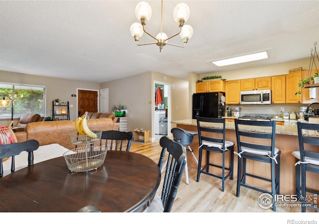1607 Rushmore Dr, Colorado Springs, CO 80910 - dining space featuring light wood-style floors, a chandelier, and a textured ceiling