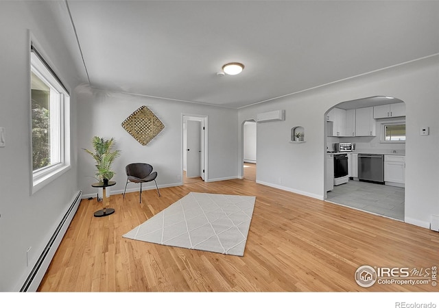 707 E Emma St, Lafayette, CO 80026 - living area with baseboard heating, arched walkways, a wall unit AC, and light wood-style flooring