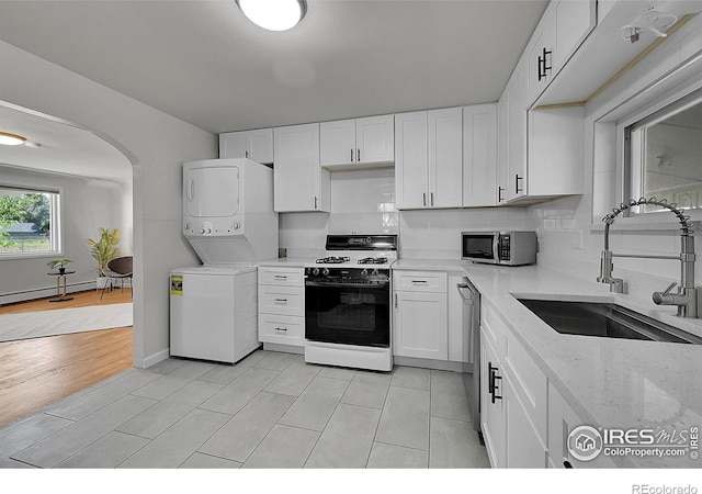 707 E Emma St, Lafayette, CO 80026 - kitchen with stainless steel appliances, stacked washing machine and dryer, baseboard heating, and white cabinetry
