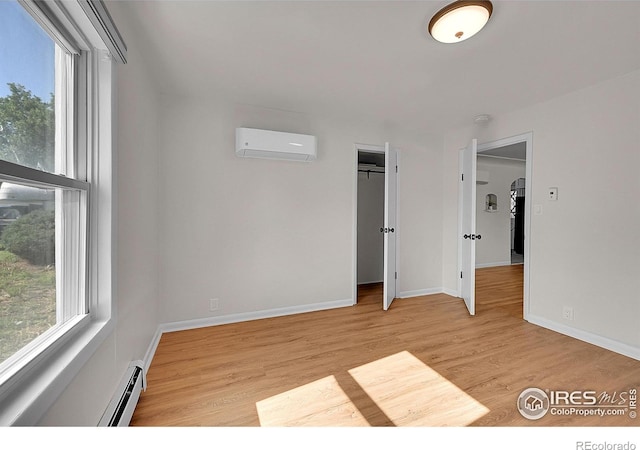 707 E Emma St, Lafayette, CO 80026 - unfurnished bedroom featuring baseboard heating, a wall unit AC, multiple windows, and light wood finished floors