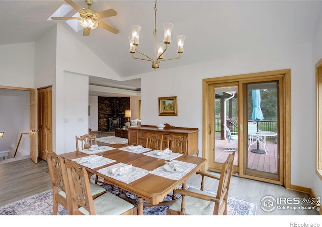 849 Mountain Meadows Rd, Boulder, CO 80302 - dining area with light wood-type flooring, a wood stove, ceiling fan, high vaulted ceiling, and a chandelier