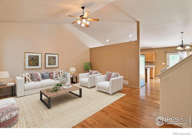 3228 Borrossa St, Evans, CO 80634 - living room featuring light wood-style flooring, a ceiling fan, a chandelier, and vaulted ceiling