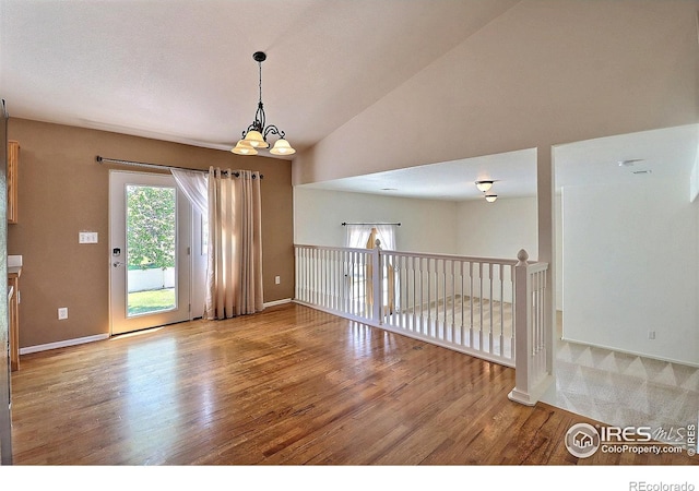 3228 Borrossa St, Evans, CO 80634 - empty room featuring wood finished floors, a chandelier, and vaulted ceiling
