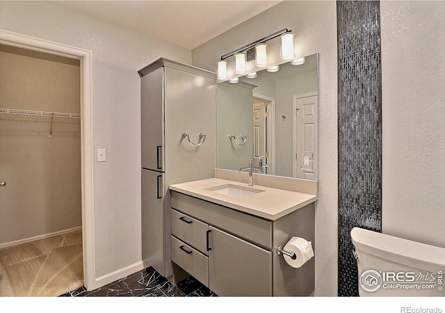 3228 Borrossa St, Evans, CO 80634 - bathroom featuring vanity, marble look tiles, and a walk in closet