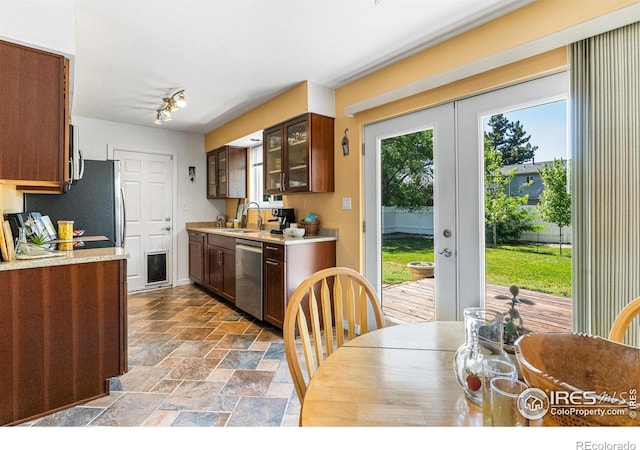109 Sunflower Dr, Windsor, CO 80550 - kitchen featuring stainless steel dishwasher, french doors, light countertops, and stone tile flooring