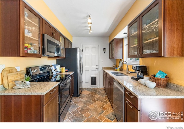 109 Sunflower Dr, Windsor, CO 80550 - kitchen featuring stainless steel appliances, dark stone finish floors, glass insert cabinets, and light stone counters