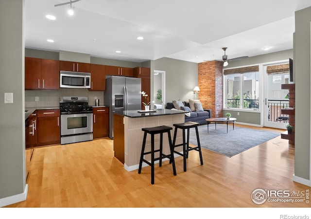 3601 Arapahoe Ave Unit 304, Boulder, CO 80303 - kitchen featuring stainless steel appliances, light wood finished floors, a kitchen bar, open floor plan, and a ceiling fan