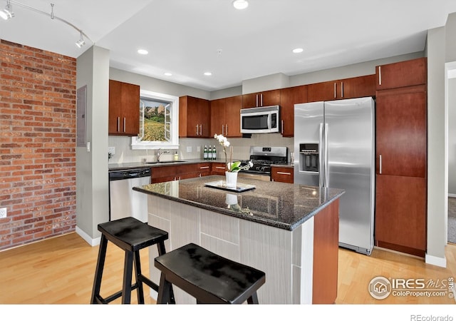 3601 Arapahoe Ave Unit 304, Boulder, CO 80303 - kitchen featuring stainless steel appliances, brick wall, light wood-style flooring, a breakfast bar, and dark stone countertops