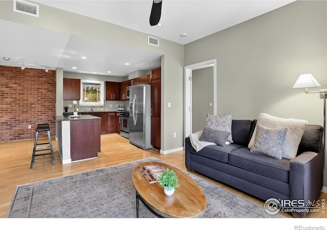 3601 Arapahoe Ave Unit 304, Boulder, CO 80303 - living area with light wood-style floors, brick wall, and a ceiling fan