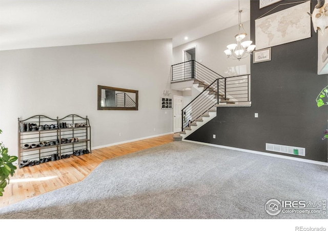 232 Ricker Ln, Johnstown, CO 80534 - unfurnished living room with stairs, carpet flooring, a chandelier, high vaulted ceiling, and wood finished floors