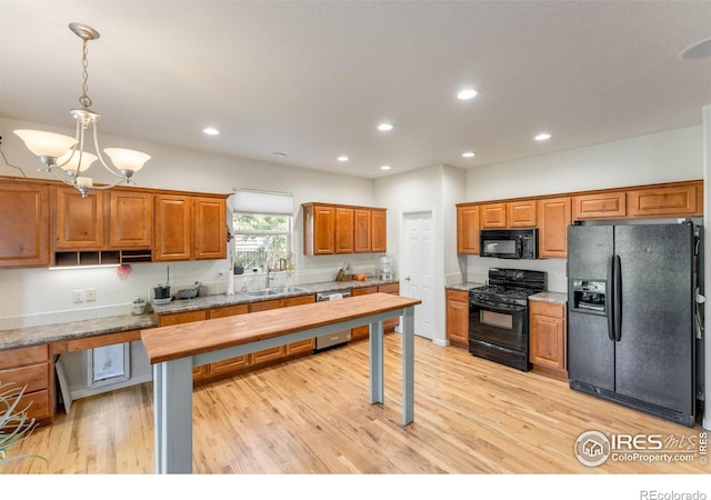 232 Ricker Ln, Johnstown, CO 80534 - kitchen featuring black appliances, brown cabinetry, light wood-style floors, recessed lighting, and a chandelier