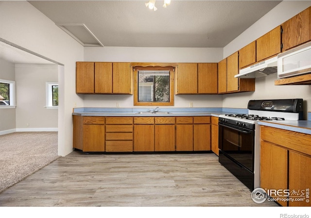 311 12th Ave, Greeley, CO 80631 - kitchen with gas stove, under cabinet range hood, light countertops, and brown cabinets