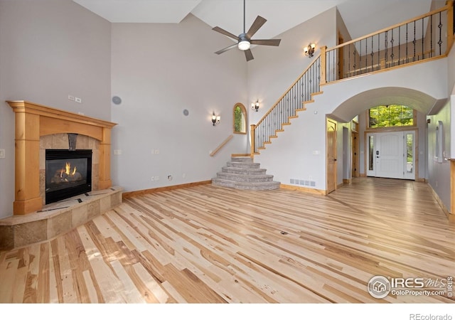 8416 Starfish Ct, Windsor, CO 80528 - unfurnished living room featuring high vaulted ceiling, wood finished floors, stairway, arched walkways, and a ceiling fan