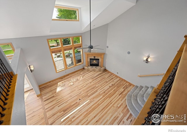 8416 Starfish Ct, Windsor, CO 80528 - unfurnished living room with high vaulted ceiling, wood finished floors, a tile fireplace, ceiling fan, and stairs