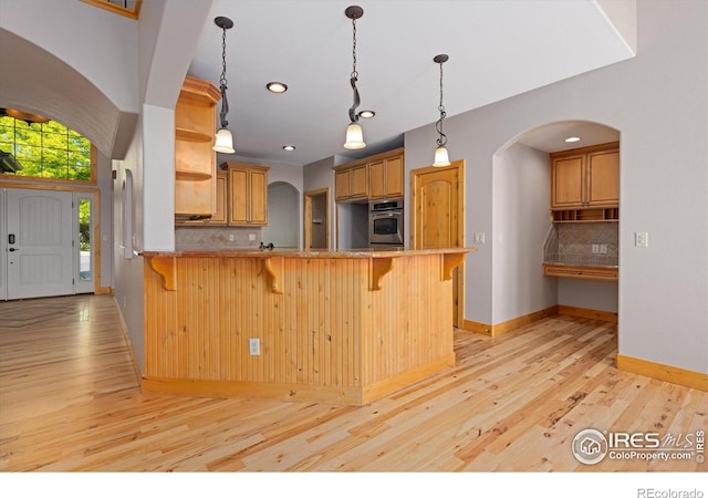 8416 Starfish Ct, Windsor, CO 80528 - kitchen featuring stainless steel oven, arched walkways, open shelves, light wood finished floors, and recessed lighting