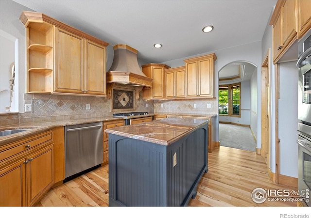 8416 Starfish Ct, Windsor, CO 80528 - kitchen featuring dishwasher, premium range hood, arched walkways, light wood-style flooring, and open shelves