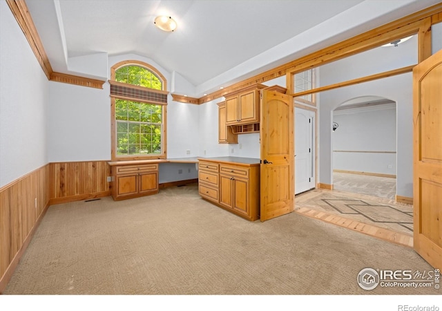 8416 Starfish Ct, Windsor, CO 80528 - kitchen with lofted ceiling, wainscoting, arched walkways, light colored carpet, and wood walls