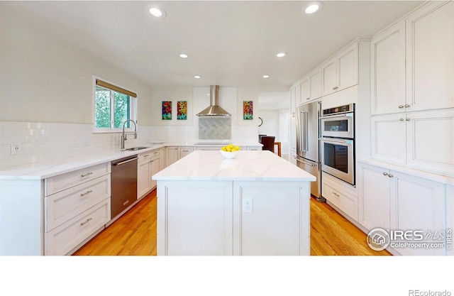 14652 Kalamath Ct, Westminster, CO 80023 - kitchen with appliances with stainless steel finishes, wall chimney exhaust hood, a center island, backsplash, and light stone counters