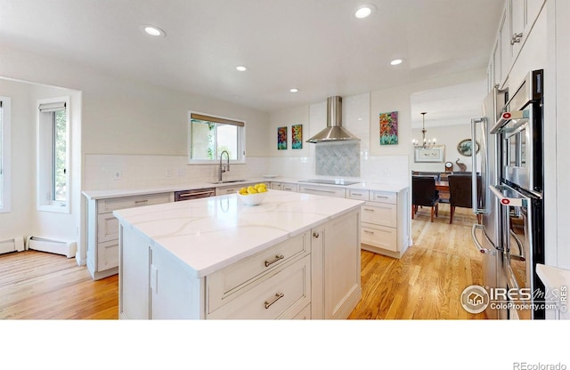 14652 Kalamath Ct, Westminster, CO 80023 - kitchen featuring wall chimney exhaust hood, light wood-style floors, light stone counters, tasteful backsplash, and white cabinetry