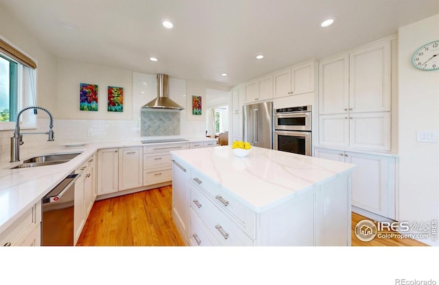 14652 Kalamath Ct, Westminster, CO 80023 - kitchen with stainless steel appliances, wall chimney range hood, white cabinets, light wood-style flooring, and decorative backsplash