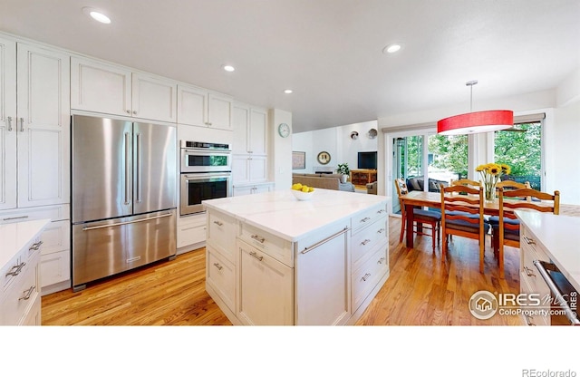 14652 Kalamath Ct, Westminster, CO 80023 - kitchen with stainless steel appliances, light wood finished floors, white cabinets, a kitchen island, and recessed lighting