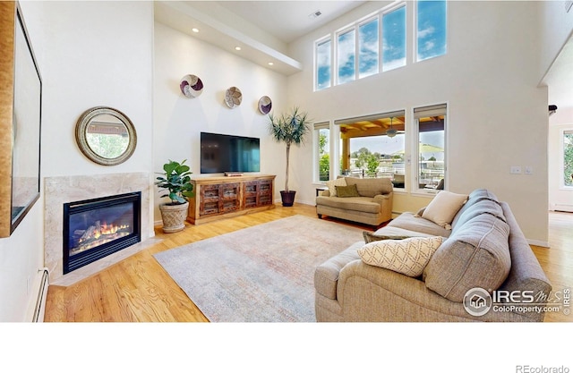14652 Kalamath Ct, Westminster, CO 80023 - living room featuring a high ceiling, healthy amount of natural light, a baseboard radiator, wood finished floors, and a premium fireplace