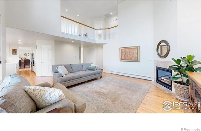 14652 Kalamath Ct, Westminster, CO 80023 - living room featuring a baseboard heating unit, wood finished floors, a high ceiling, a fireplace, and recessed lighting