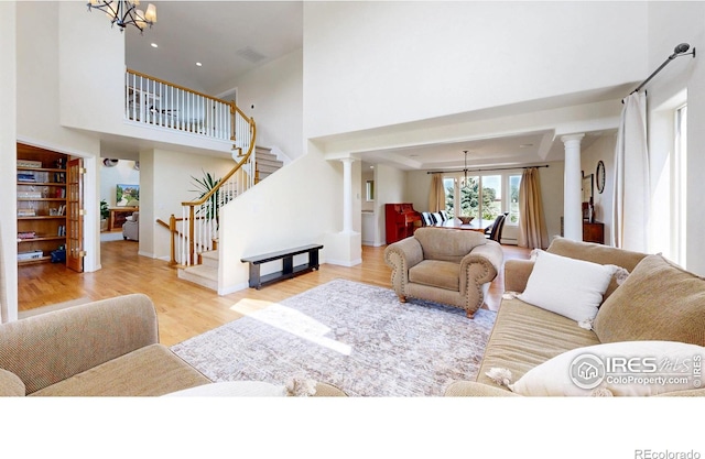14652 Kalamath Ct, Westminster, CO 80023 - living room with decorative columns, a high ceiling, wood finished floors, stairway, and a chandelier