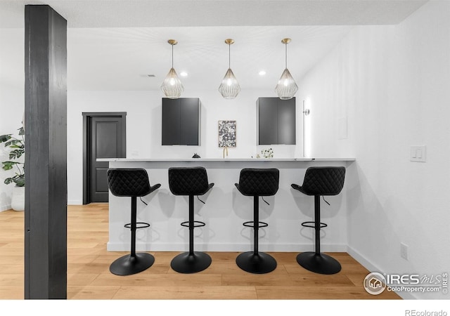 5056 Blanchette St, Timnath, CO 80547 - kitchen with light wood-style floors, a kitchen breakfast bar, decorative light fixtures, a peninsula, and recessed lighting