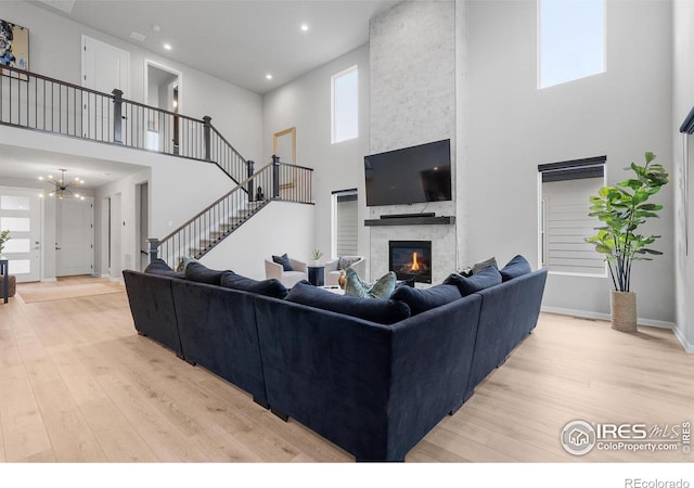 5056 Blanchette St, Timnath, CO 80547 - living area featuring a high ceiling, light wood-style flooring, a fireplace, a chandelier, and stairs
