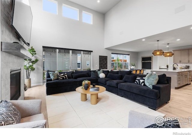5056 Blanchette St, Timnath, CO 80547 - living room featuring light wood-style floors, a towering ceiling, a glass covered fireplace, and recessed lighting