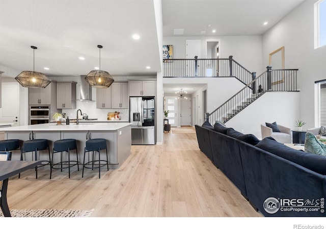 5056 Blanchette St, Timnath, CO 80547 - kitchen with appliances with stainless steel finishes, wall chimney range hood, recessed lighting, light wood-type flooring, and a breakfast bar