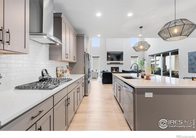 5056 Blanchette St, Timnath, CO 80547 - kitchen with wall chimney exhaust hood, appliances with stainless steel finishes, open floor plan, backsplash, and light wood-style floors