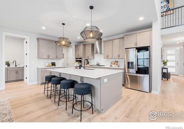 5056 Blanchette St, Timnath, CO 80547 - kitchen featuring appliances with stainless steel finishes, wall chimney exhaust hood, gray cabinetry, tasteful backsplash, and a kitchen breakfast bar
