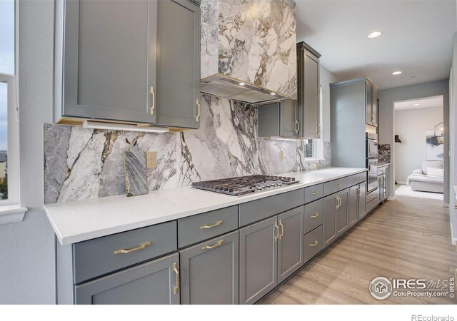 12917 Fox St, Westminster, CO 80234 - kitchen featuring extractor fan, stainless steel gas stovetop, gray cabinets, light wood-type flooring, and recessed lighting