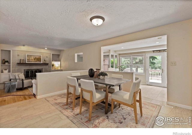 412 Terry Point Dr, Fort Collins, CO 80524 - dining room with a textured ceiling, a tile fireplace, and light wood-style flooring