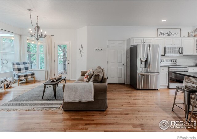 8367 Devinney St, Arvada, CO 80005 - living area with a chandelier, light wood-style floors, and recessed lighting