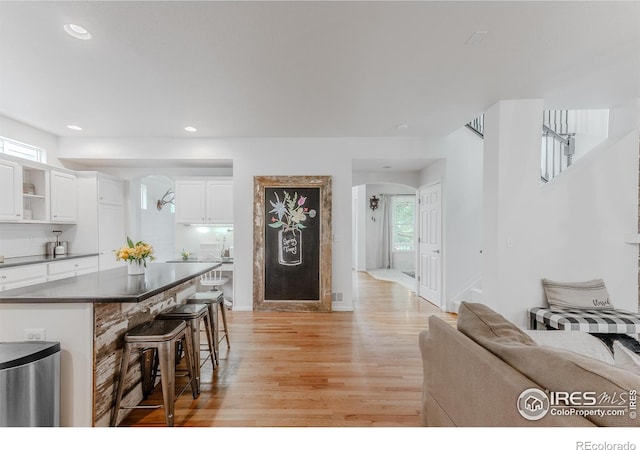 8367 Devinney St, Arvada, CO 80005 - kitchen with arched walkways, light wood-type flooring, a breakfast bar, dark countertops, and recessed lighting
