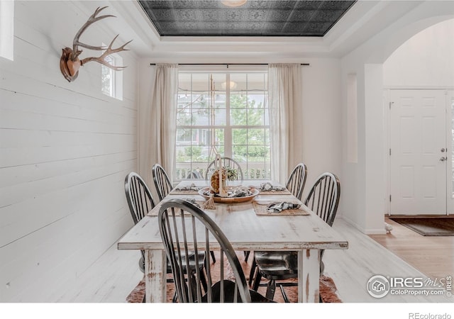 8367 Devinney St, Arvada, CO 80005 - dining room with a raised ceiling, arched walkways, light wood-style flooring, and wooden walls