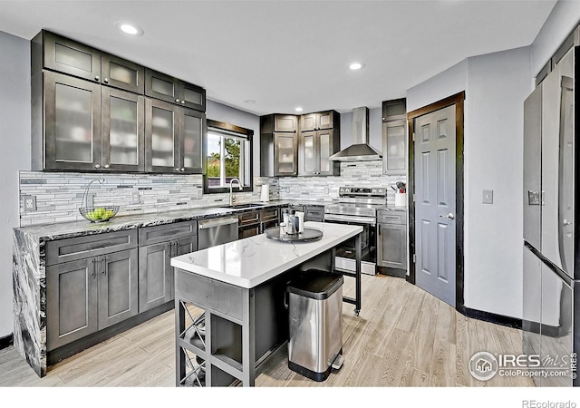 1424 Sheep Ridge Rd, Fairplay, CO 80440 - kitchen featuring wall chimney exhaust hood, stainless steel appliances, light wood-style floors, decorative backsplash, and a center island