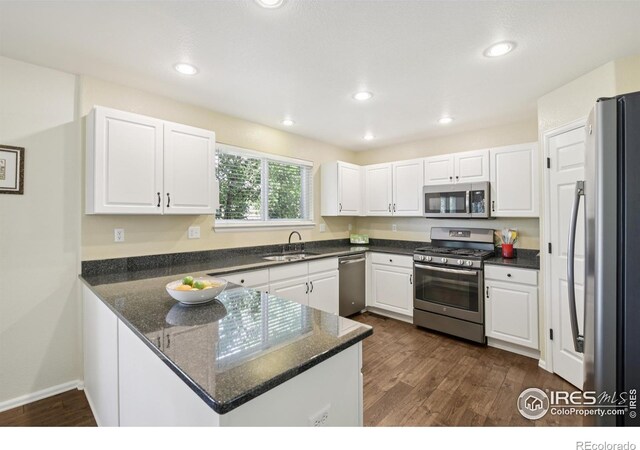 2608 E 132nd Ave, Thornton, CO 80241 - kitchen with appliances with stainless steel finishes, a peninsula, white cabinets, dark wood-type flooring, and recessed lighting