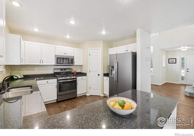 2608 E 132nd Ave, Thornton, CO 80241 - kitchen with stainless steel appliances, white cabinetry, recessed lighting, dark stone counters, and dark wood-style floors