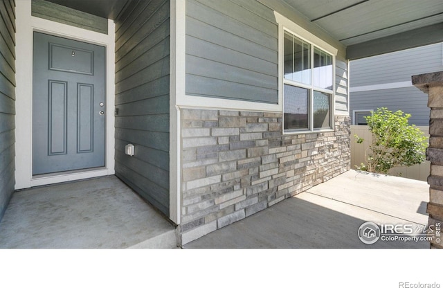 627 Overland Trl, Ault, CO 80610 - doorway to property with covered porch and stone siding
