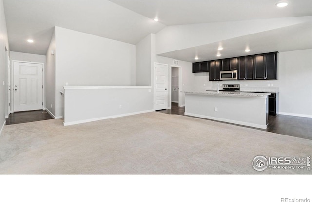 627 Overland Trl, Ault, CO 80610 - kitchen featuring stainless steel microwave, lofted ceiling, recessed lighting, dark carpet, and light countertops