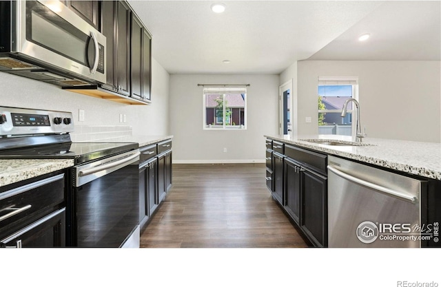 627 Overland Trl, Ault, CO 80610 - kitchen featuring stainless steel appliances, dark wood-style flooring, plenty of natural light, light stone counters, and recessed lighting